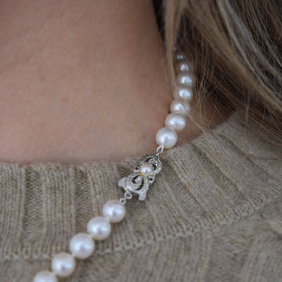 This delicate freshwater pearl necklace features a charming bow design.