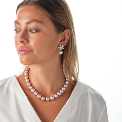 Model wearing flower earrings and necklace featuring Kasumiga pearls and diamonds in 18K White Gold. 